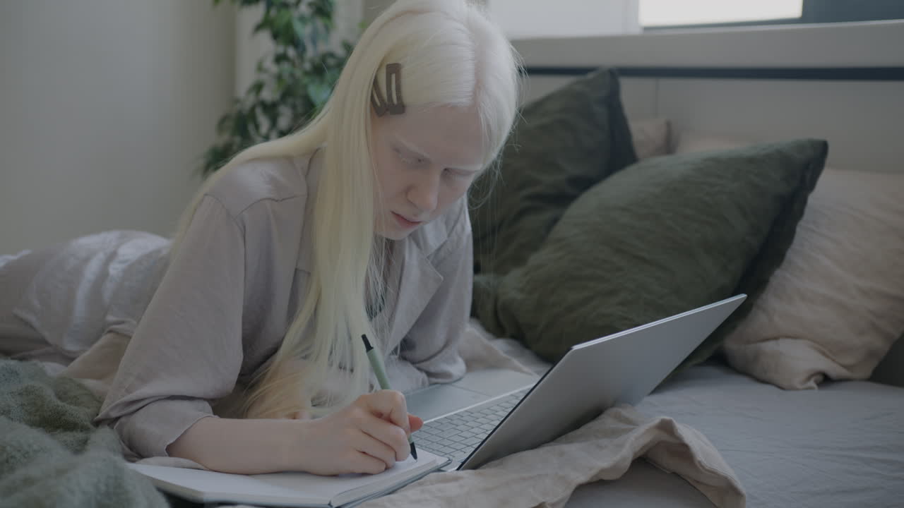 Woman Studying on a Laptop in Bed