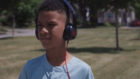 young african american kid close up listening to music outdoors on headphones