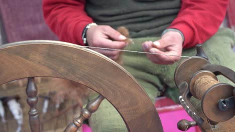 a street artist sewing manufacturing with traditional spinning wheel