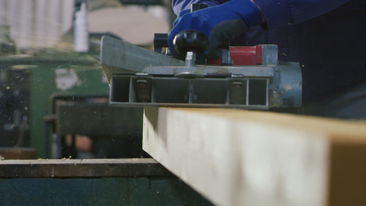 Makro-Nahaufnahme eines professionellen Tischlers, der an Holzbearbeitungsmaschinen in einer Werkstatt einer Holzfabrik arbeitet