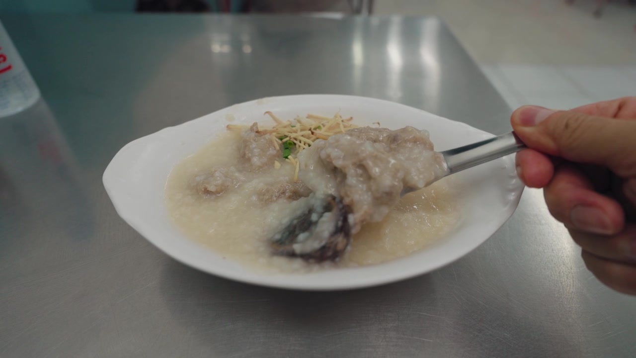Orang Makan Bubur Nasi Tradisional Asia dengan Telur Pitan