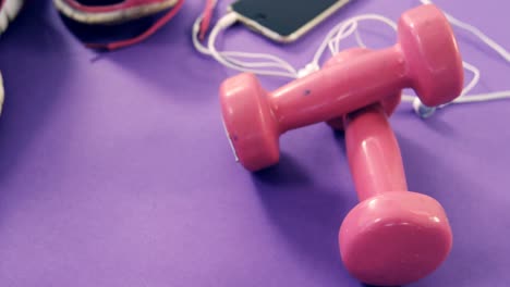 Mobile-phone-with-headphones,-shoes-and-dumbbells-on-table