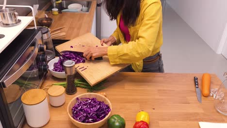 woman chopping red cabbage in kitchen