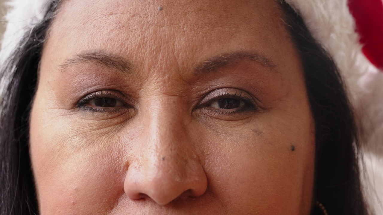 At christmas, Close-up of woman wearing Santa hat, smiling warmly during holiday celebration