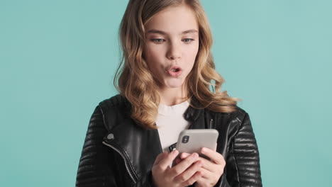 una adolescente caucásica con una chaqueta de cuero usando su teléfono inteligente.