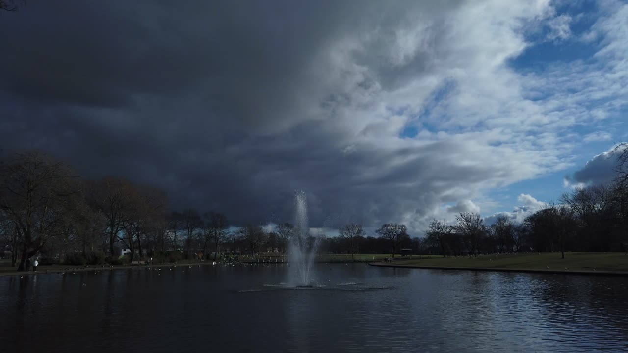 평화로운 공원 호수 분수 위의 무겁고 위협적인 어두운 폭풍 구름