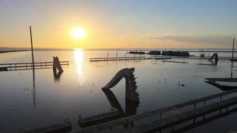 Peaceful-sunset-view-of-abandoned-villa-epecuen,-popular-freshwater-pool-spa-overfilled-with-salty-flood-water,-aerial-pan-shot-capturing-ruins-of-poolside-slides-and-railing