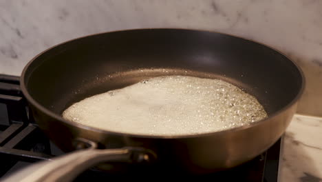 Handheld-shot-of-hot-butter-being-browned-in-a-modern-non-stick-pan