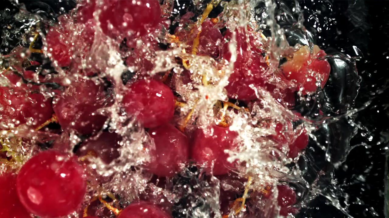 Uva rossa fresca che schizza con l'acqua al rallentatore.