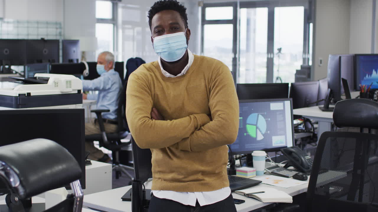 Man wearing face mask crossing his arms while standing in office
