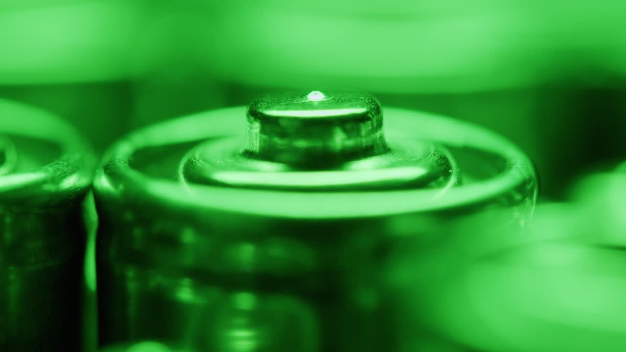 Silver batteries AA and AAA in neon light close-up macro. Double-A battery is a standard size single cell cylindrical dry battery. Batteries are common in portable electronic devices. An AA battery is composed of a single electrochemical cell that may be either a primary battery or a rechargeable ba