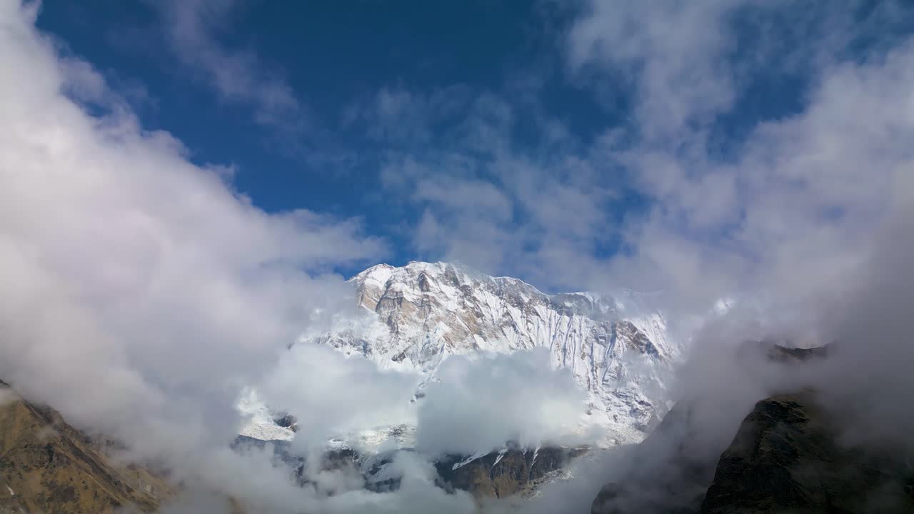 Majestic Dhaulagiri peaks rise through drifting clouds along the Annapurna Circuit, Nepal, showcasing rugged rocky slopes, snowy summits, and breathtaking Himalayan wilderness in soft morning light