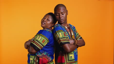 serious proud ethnic couple standing back to back in studio