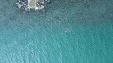 a lone scuba diver swimming deep underwater viewed from high above the ocean