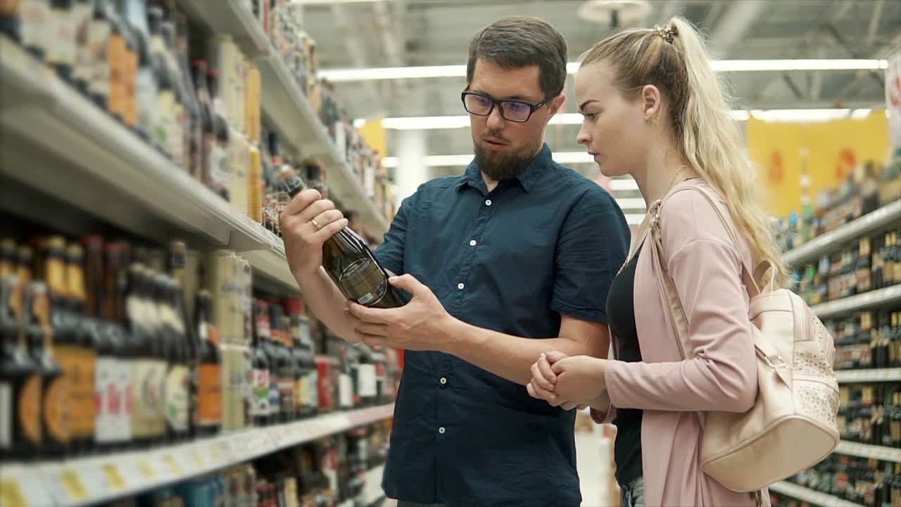 pareja comprando cerveza y vino en una tienda de comestibles