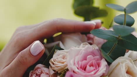 woman with beautiful manicure touches fresh flower bouquet