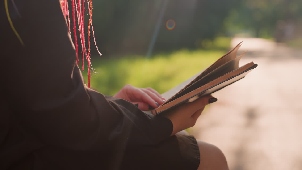 Sendero iluminado por el sol con una persona pensativa, escena serena con una persona absorta en sus recuerdos a la luz del sol, entorno tranquilo al aire libre con alguien concentrado en un libro a lo largo de un sendero bañado por el sol