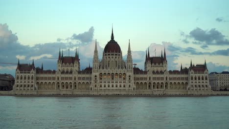 people walk on the closed lower quay due to the high water level of the river danube in front of the hungarian parliament building during dusk in budapest, hungary.