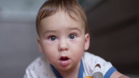 little cute grey-eyed baby boy looking at camera. portrait of a lovely caucasian kid close up. blurred backdrop.