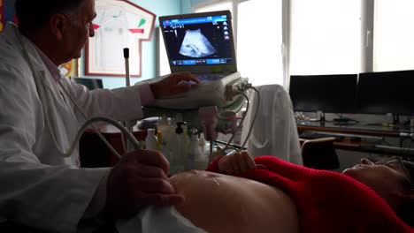 gynecologist lowers the ultrasound screen so his pregnant patient could see the baby