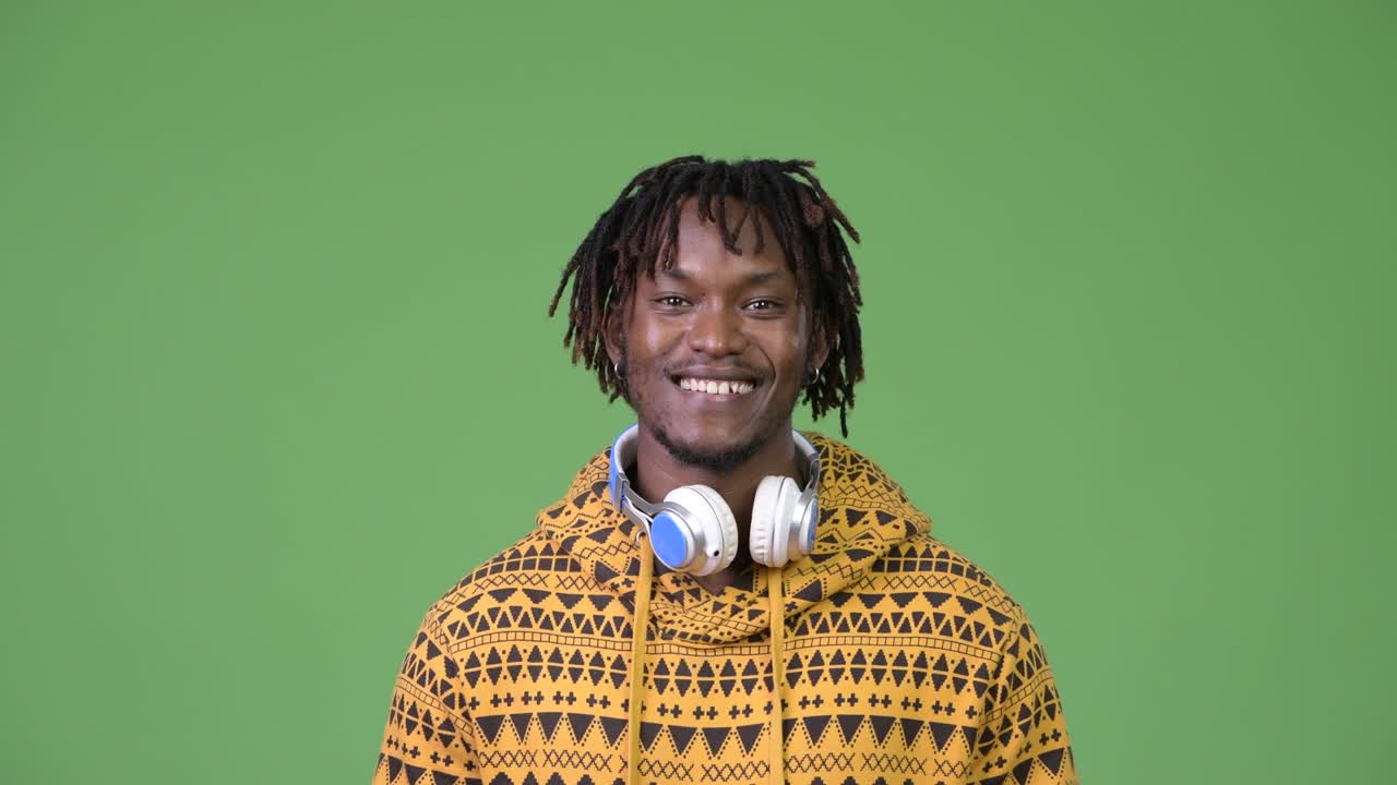 Giovane, bello e felice uomo africano che sorride indossando le cuffie