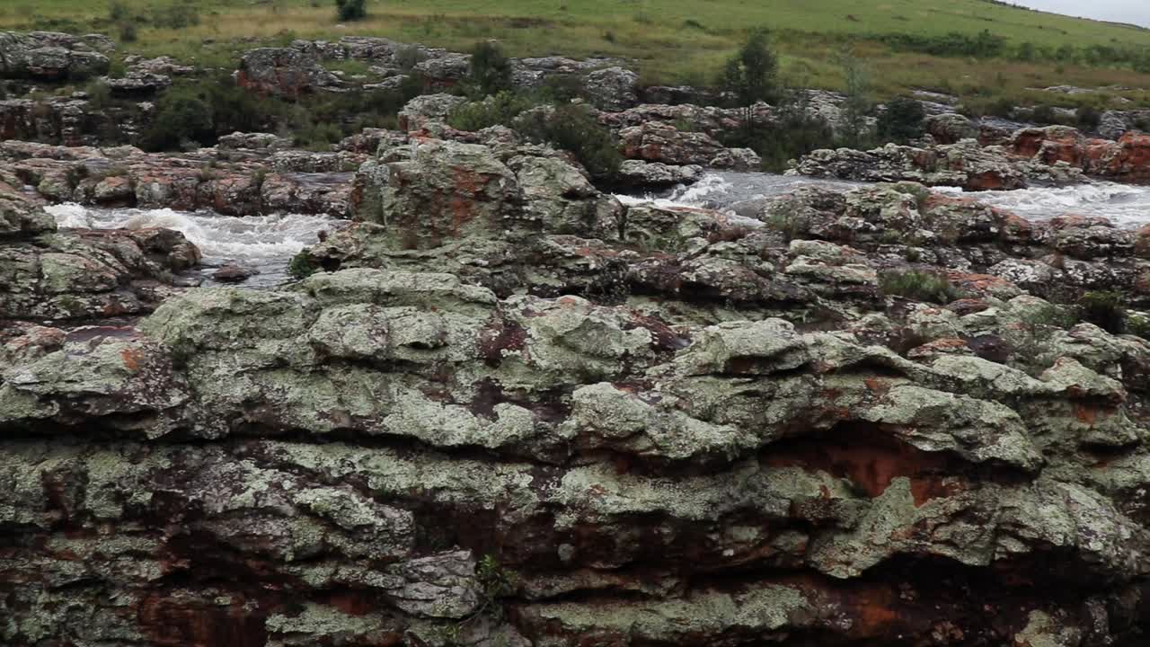 toma panorámica de una pequeña caída de agua con rápidos que se mueven rápidamente en el fondo