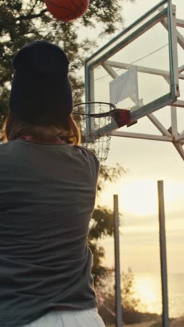 person shooting a basketball at sunset