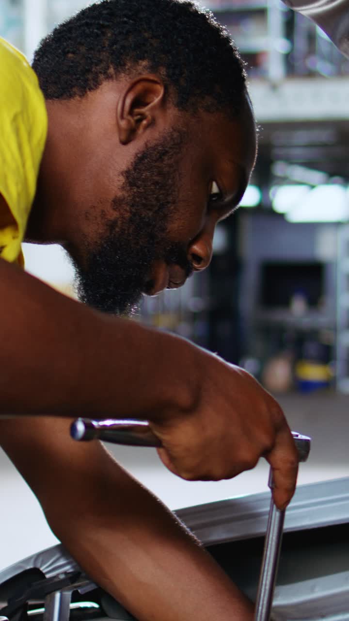 Vertical video Worker replaces car engine in garage