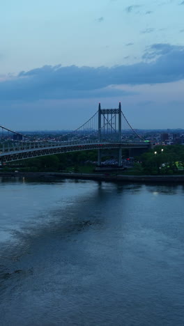 ferry boat floating by east river. beautiful triborough bridge with transport going by and under it. evening time in new york. vertical video