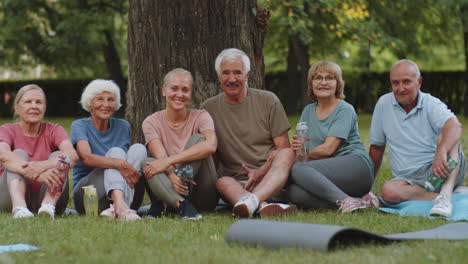 portrait of positive elderly people and fitness coach in park