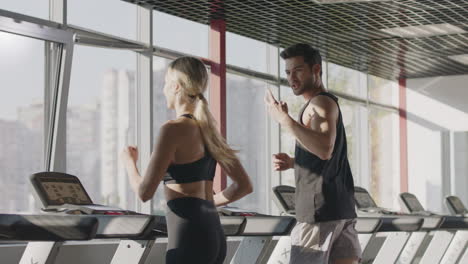 Running-couple-training-cardio-exercise-on-treadmill-machine-in-fitness-center