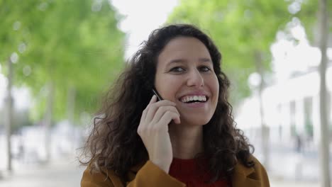 Happy-young-woman-talking-by-cell-phone-outdoor