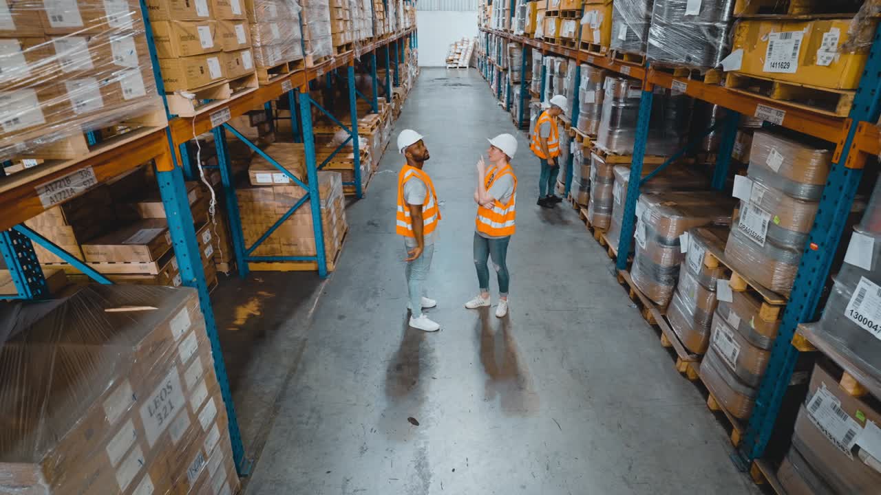 High angle view of warehouse workers discussing in the distribution center view of the forklift