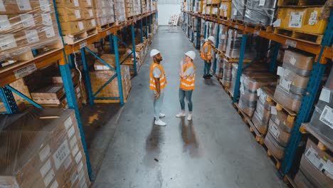 high angle view of warehouse workers discussing in the distribution center view of the forklift