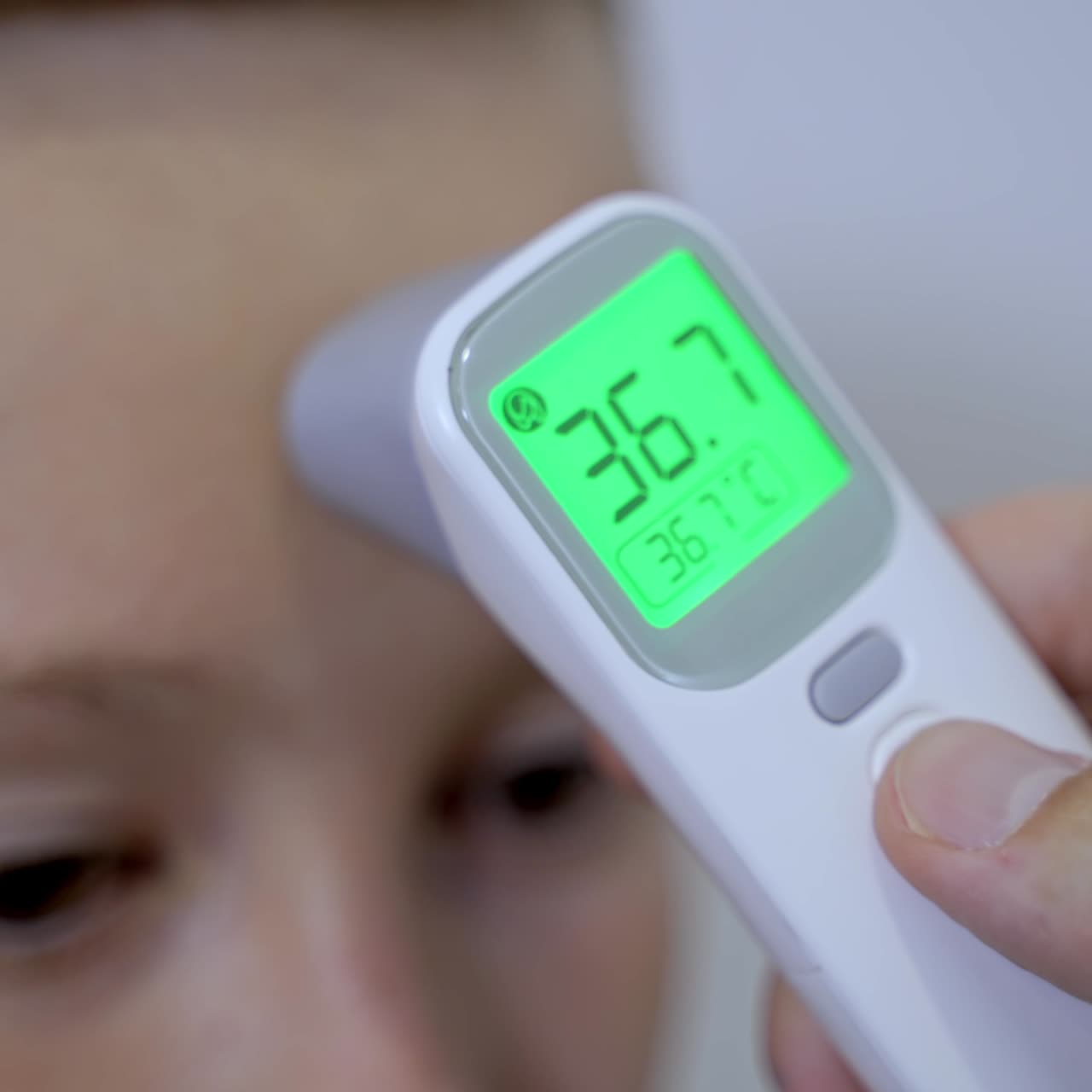 Doctor measuring temperature of boy with infrared thermometer at hospital. Medical check-up