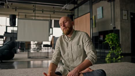 man stretching and meditating in a modern office