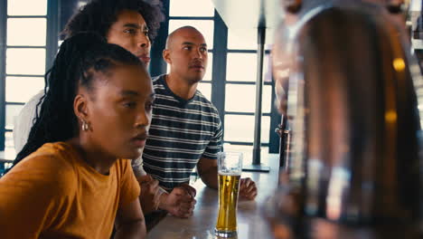 Grupo-Multicultural-Decepcionado-De-Amigos-En-Un-Bar-Deportivo-Viendo-Al-Equipo-Perder-El-Juego-En-La-Televisión