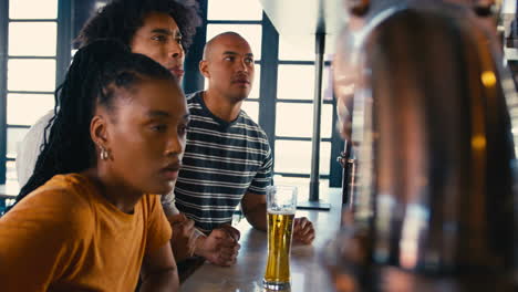un grupo de amigos multiculturales decepcionados en un bar deportivo viendo al equipo perder el juego en la televisión