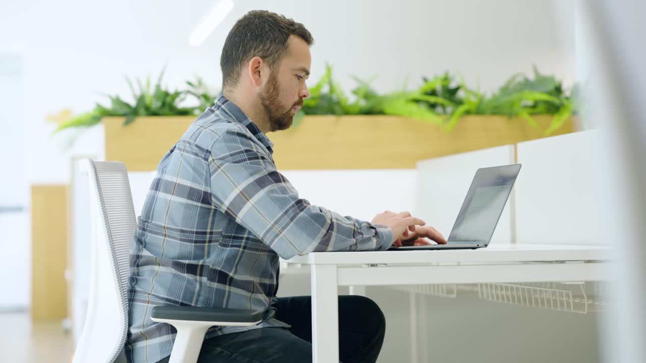 Focused employee working on laptop in modern office