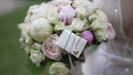 Capture-the-bride's-elegant-moment-as-she-holds-a-bouquet-adorned-with-a-golden-necklace,-showcasing-bridal-beauty-and-sophistication-on-her-special-day