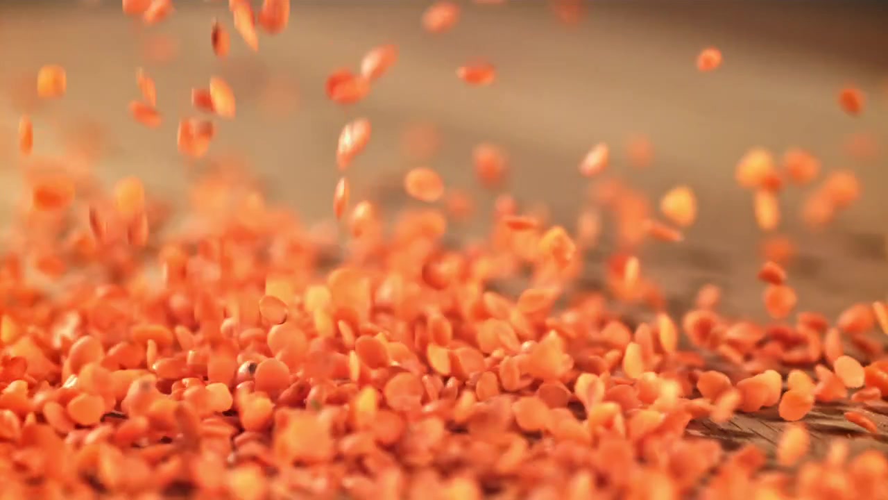Red Lentils Falling onto a Wooden Surface in Slow Motion
