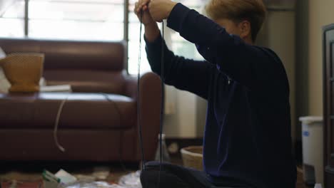 person sitting on the floor manipulating a black cord