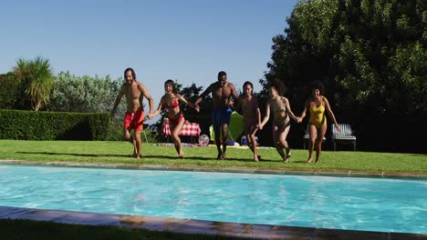 diverse group of friends having fun jumping into a swimming pool