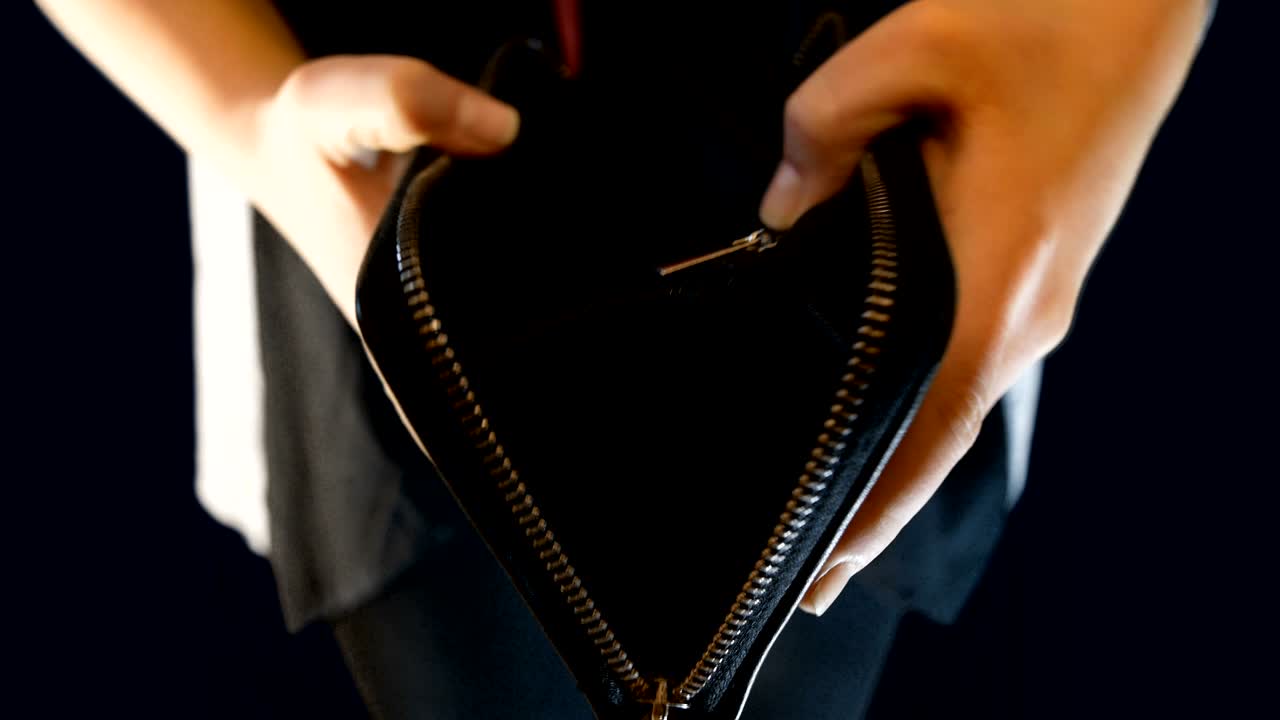 una adolescente sostiene una billetera, la abre y no hay dinero en ella, imágenes adecuadas para hablar de la pobreza, la supervivencia y los problemas de trabajo