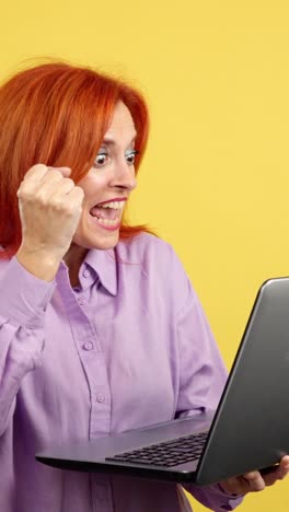 excited red-haired woman celebrating success with laptop