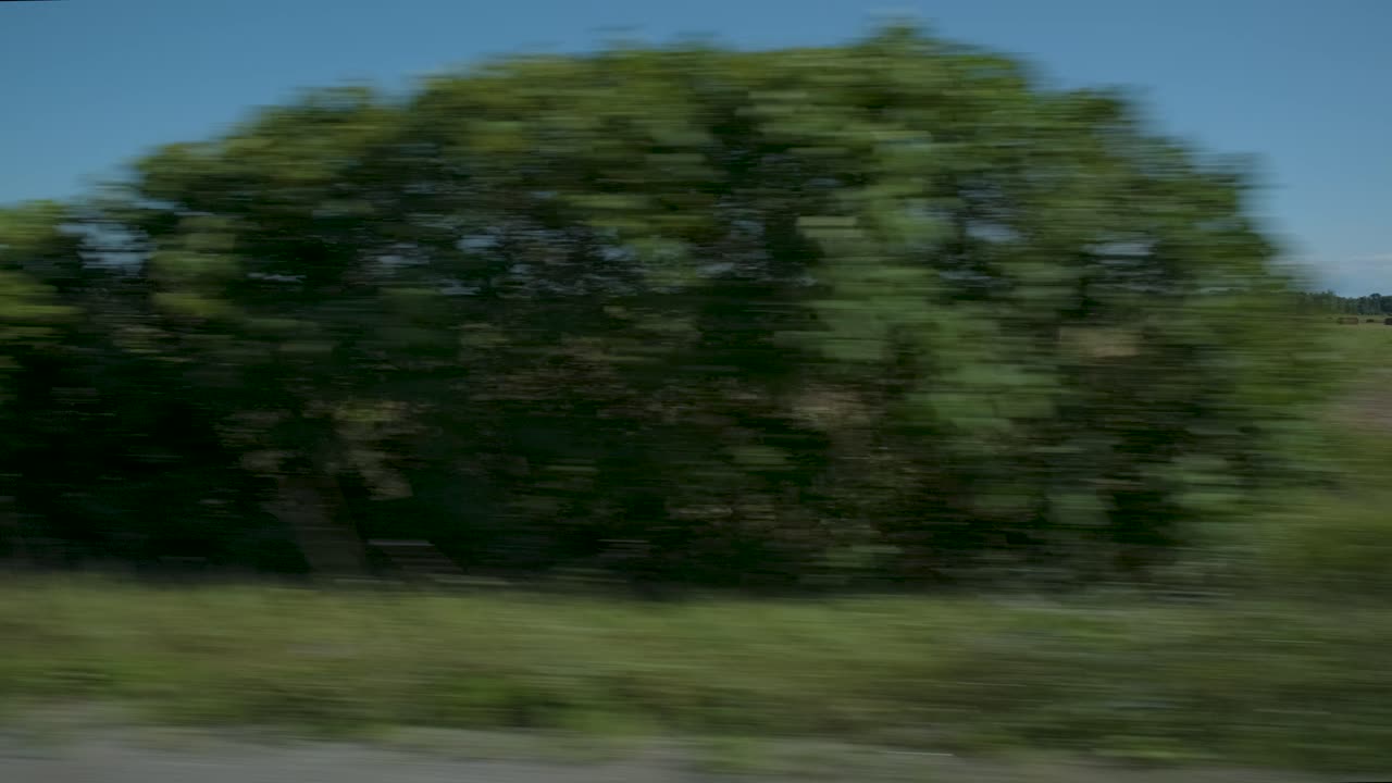 Car moving with speed at the side of a farming field at Prince Edward County