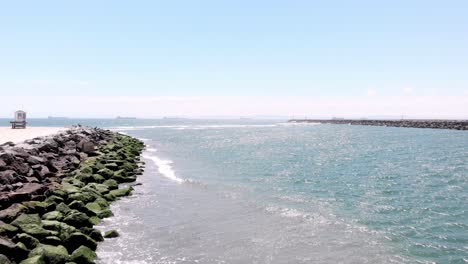 drone shot with rocky beach and lifeguard shack