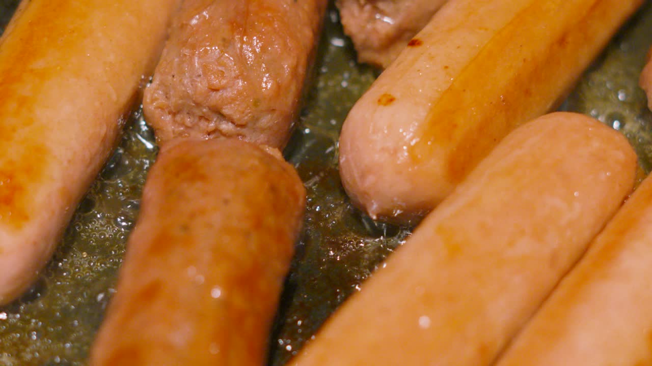 Top View of Oil Bubbling in Slow Motion with Meatless Sausages Being Cooked. Carbon Friendly Meat Alternative Food Cooking in Frying Pan. Processed with Natural Ingredients