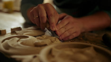 unknown man making ornament on wood indoors. carpenter hands carving wood