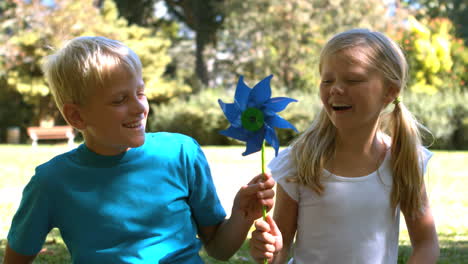 siblings blowing a pinwheel together